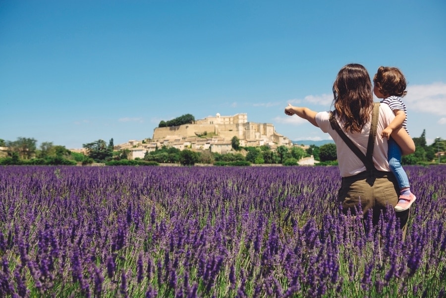 mother with daughter in a lavender field with a hilltop town in the background