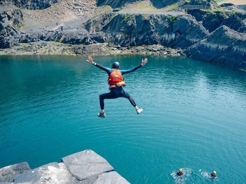 person jumping from a cliff with arms wide strechted out